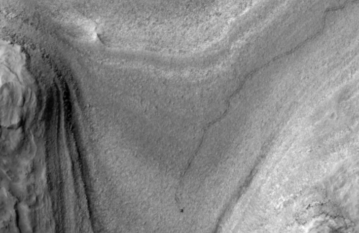 ​This eerie photograph represents the initial orbital perspective of the Curiosity rover traversing the surface of Mars.
 